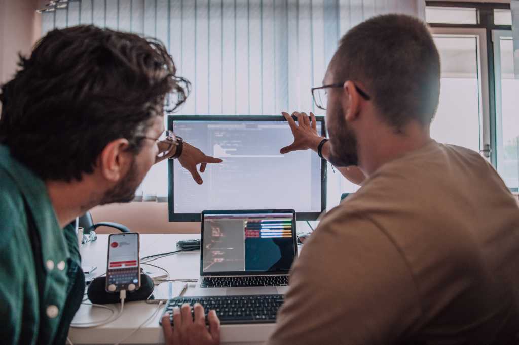 Programmers engrossed in deep collaboration, diligently working together to solve complex problems and develop innovative mobile applications with seamless functionality.